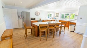 A modern kitchen with wooden cabinetry, a central island, and a dining area with wooden chairs.