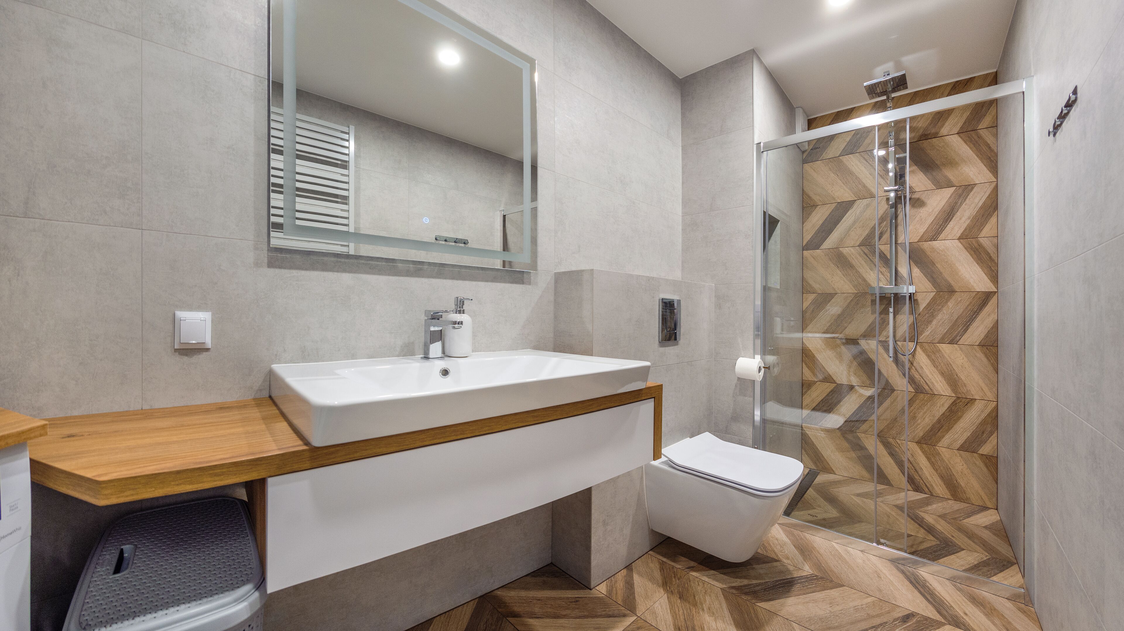 A modern bathroom with a large sink, toilet, and walk-in shower.