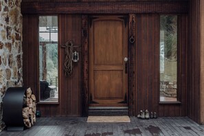 A wooden door with a doormat, a lantern, and a rope hanging on the wall.