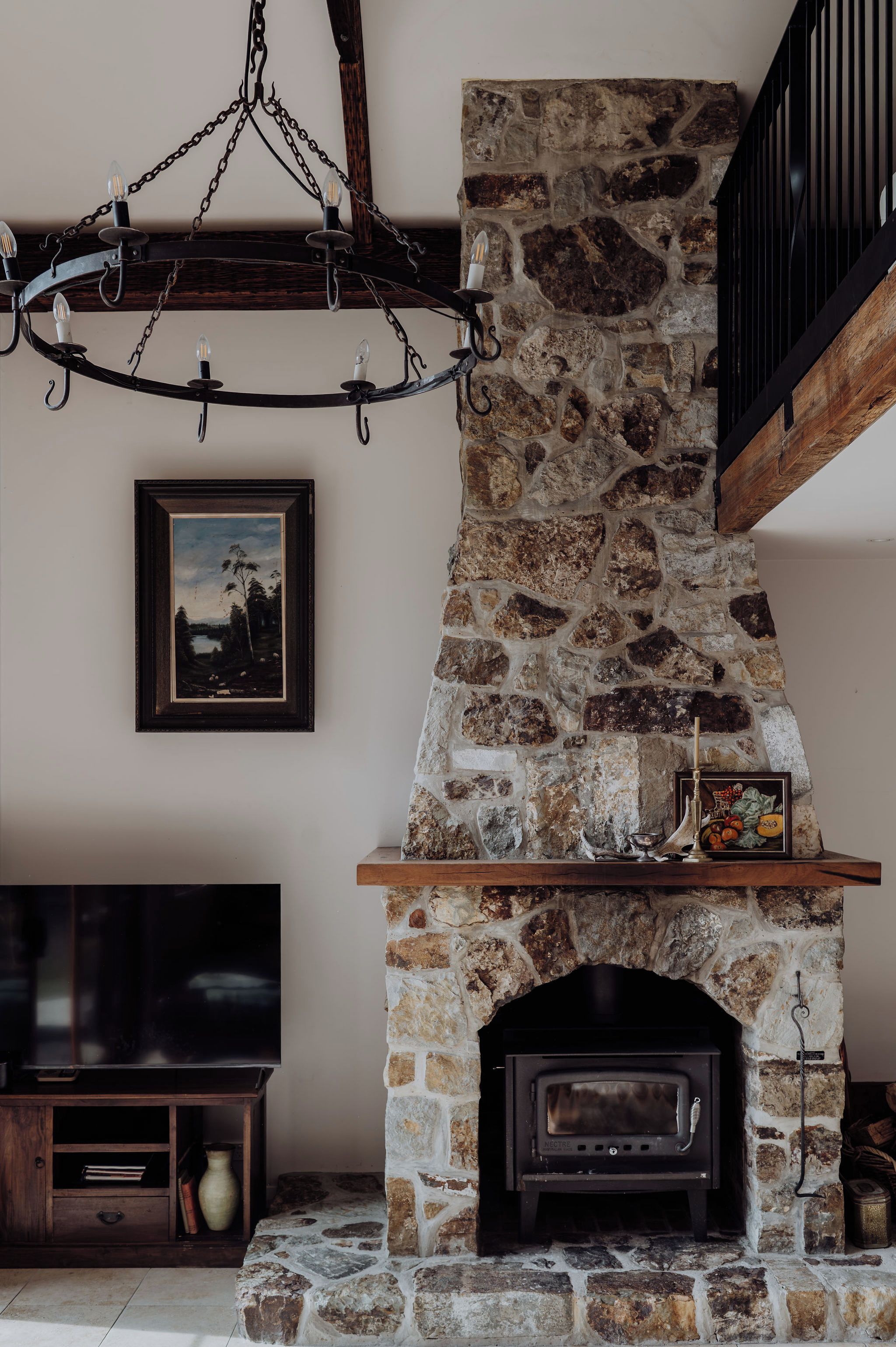 A stone fireplace with a mantel shelf, a mounted television, and a framed picture on the wall.