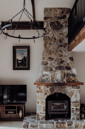 A stone fireplace with a mantel shelf, a mounted television, and a framed picture on the wall.