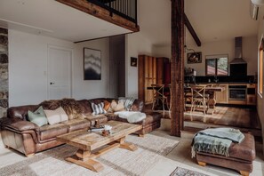 Un salon chaleureux avec un canapé en cuir marron, une table basse en bois et un coin repas comprenant des chaises et une table en bois.