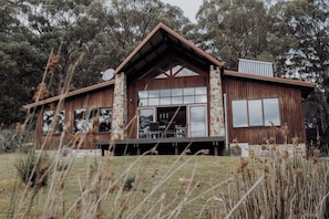 A rustic cabin with a stone foundation, large windows, and a prominent chimney. - Adventure Bay Retreat (Adventure Bay)