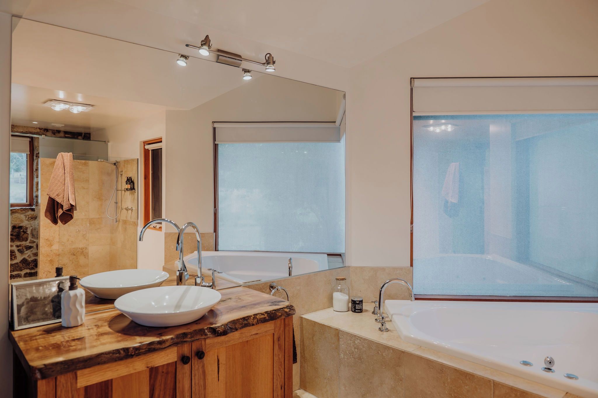 A modern bathroom with two sinks, a bathtub, and a large mirror.