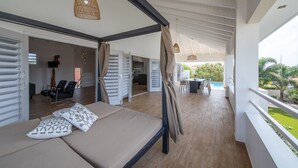 A modern bedroom with a bed, curtains, and a view of a pool and outdoor area.