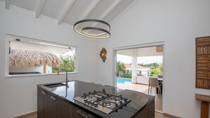 A modern kitchen with a central island, a large window, and a view of the outdoors.