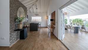 A spacious kitchen with a central island, a dining area with a table and chairs, and a view through large sliding doors to an outdoor balcony.
