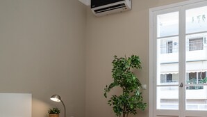 Un dormitorio con cama, lámpara de noche, aire acondicionado y una planta en maceta.
