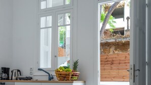 Una cocina moderna con armarios blancos, encimera de madera y una ventana con persianas.