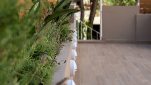 Una terraza de madera con una jardinera llena de plantas verdes y un árbol al fondo.