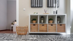 Una sala moderna con una mesa consola blanca, cestas de mimbre y un suelo estampado.