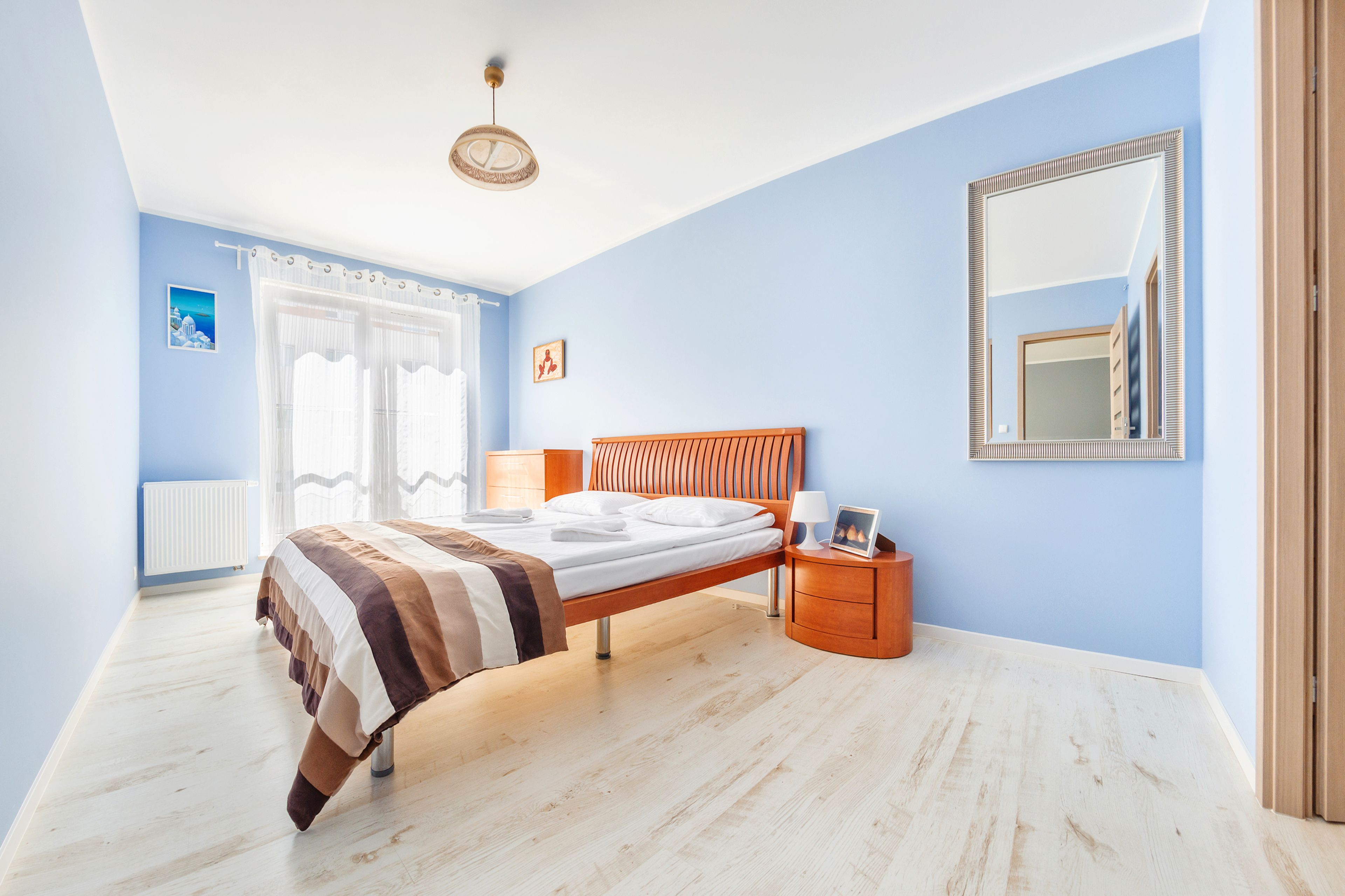 Ein Schlafzimmer mit Bett, Nachttisch und einem großen Spiegel an der Wand.