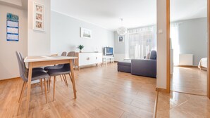 A modern living room with a dining area, a sofa, and a TV. - Apartamenty Sun & Snow Rybacka (Wladyslawowo)