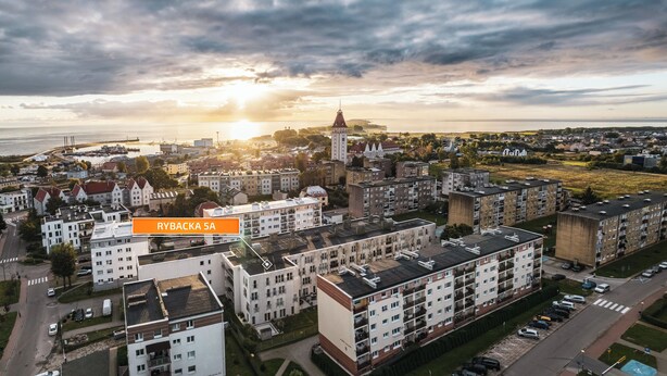 An aerial view of Rybacka 5A, featuring a mix of residential buildings, a prominent church, and a Ferris wheel in the background. - Apartamenty Sun & Snow Rybacka (Wladyslawowo)