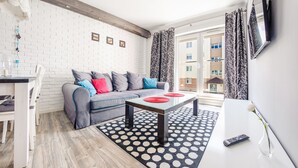 A modern living room with a grey sofa, a white coffee table, and a black and white patterned rug. - Apartamenty Sun & Snow Rybacka (Wladyslawowo)