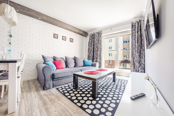 A modern living room with a grey sofa, a white coffee table, and a black and white patterned rug.