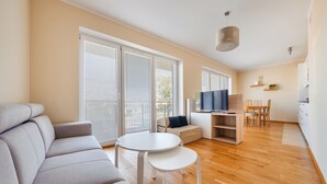 A modern living room with a sofa, a small round table, and a TV. - Apartamenty Sun & Snow Rybacka (Wladyslawowo)