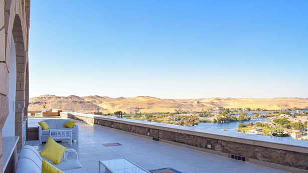 A terrace with outdoor seating and a view of a river and hills. - Basma Executive Club (Aswan)