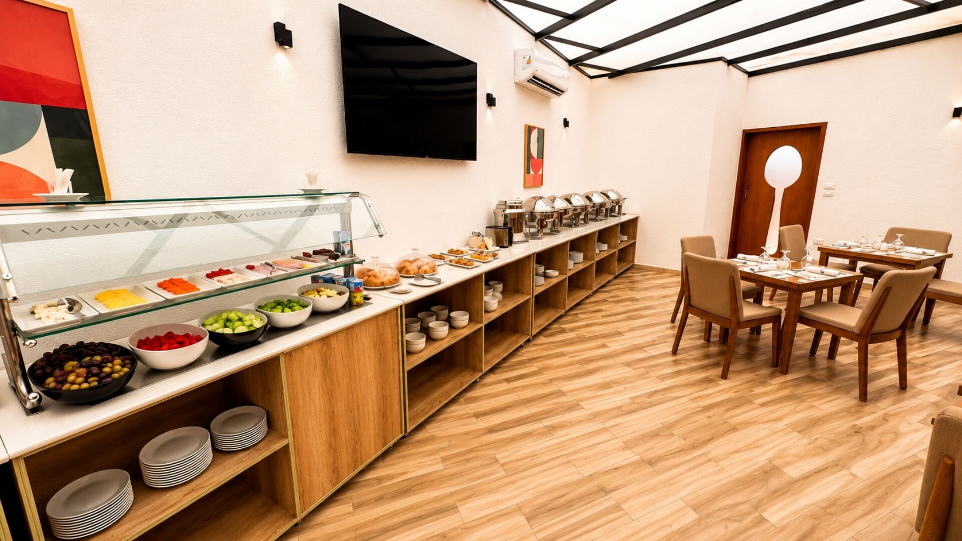 Un espace buffet proposant une variété de plats, un téléviseur et un coin salon avec des tables et des chaises.