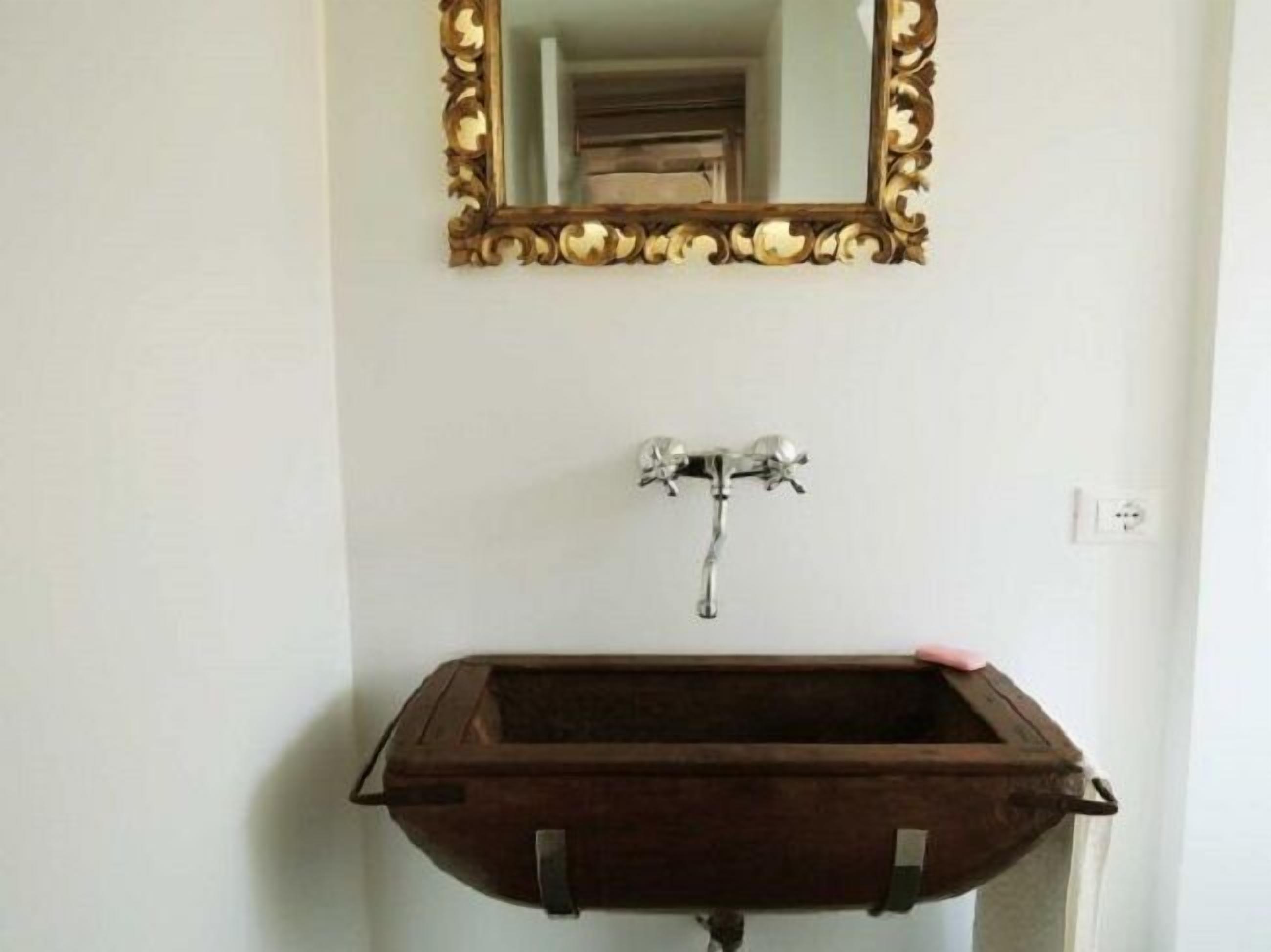 A bathroom with a wooden sink and a mirror with an ornate gold frame.
