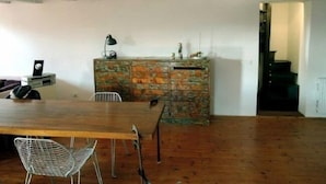 A room with a wooden dining table, metal chairs, a camouflage-patterned cabinet, and a staircase leading to an upper level. - Venezianamente - Ca'Zane (Venice)