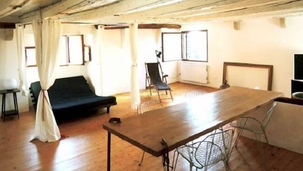 A rustic room with a wooden table, a black sofa, and a metal chair. - Venezianamente - Ca'Zane (Venice)
