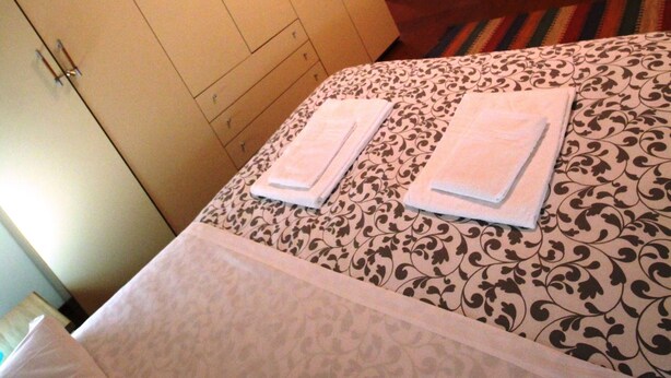 A bedroom with a bed, two towels, a mirror, and a wardrobe. - Venezianamente - Casa del Batelo (Venice)