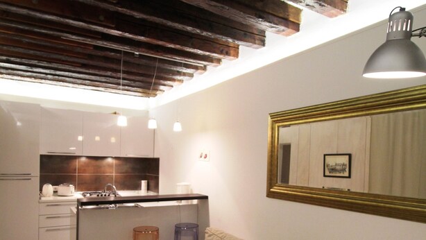 A modern kitchen with white cabinets, a wooden island, and pendant lighting. - Venezianamente - Casa dell'Orio (Venice)