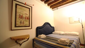 A bedroom with a bed, a framed picture on the wall, a bedside table, and a lamp. - Venezianamente - Casa dell'Orio (Venice)