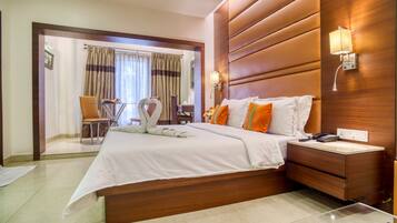 A hotel room with a large bed, a bedside table with a lamp, a chair, and a view of the bathroom through an open door.
