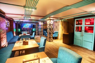 Un ristorante moderno con sedute blu, tavoli in legno e tubature a vista al soffitto.