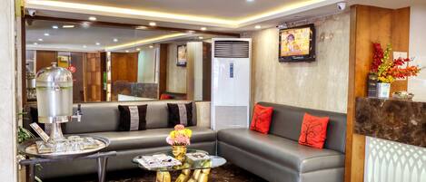 A modern hotel lobby with a sofa, a coffee machine, and a decorative vase.
