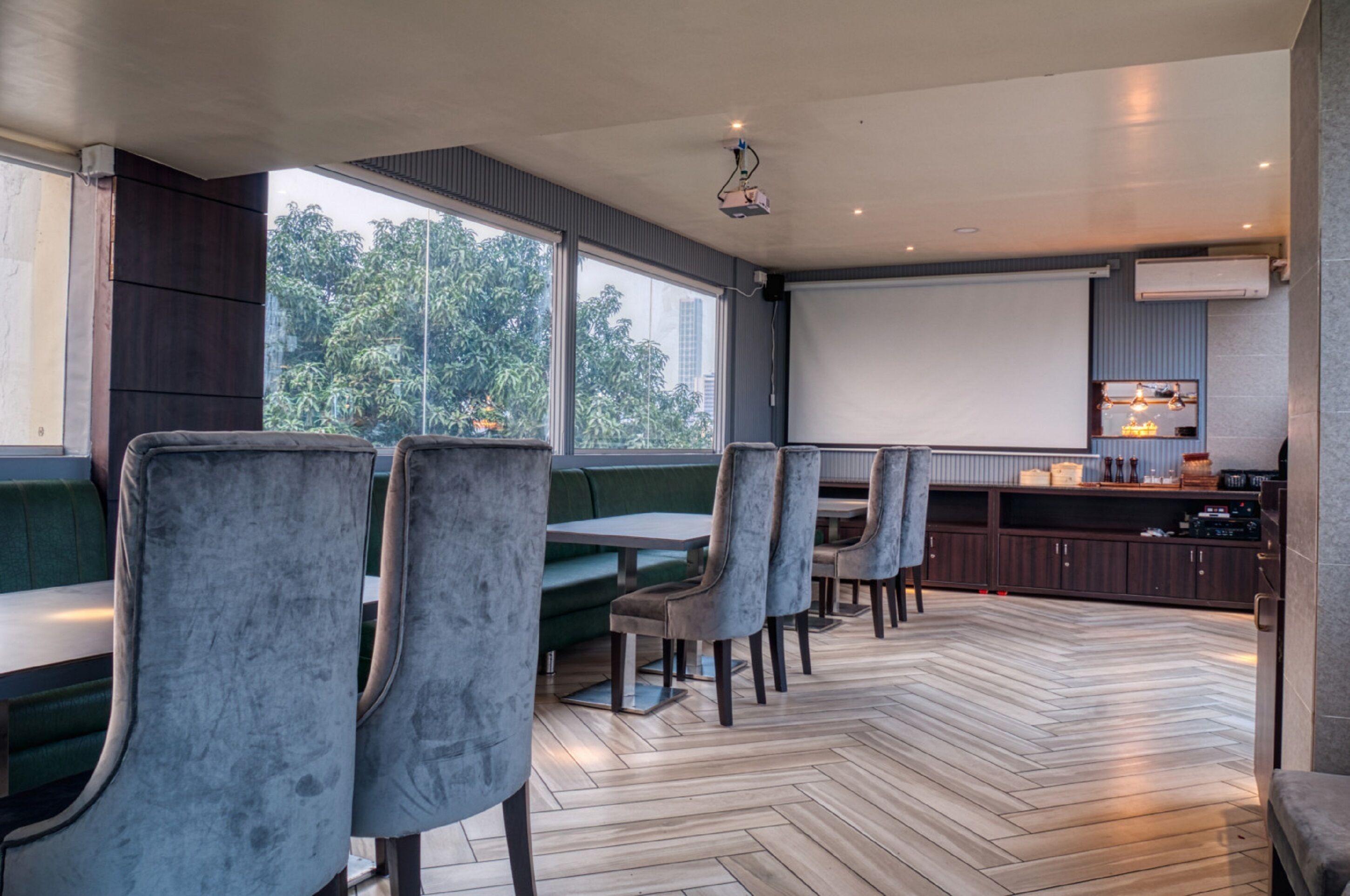 Un restaurante moderno con asientos tipo banca tapizados en gris y suelo de madera con diseño de espiga.