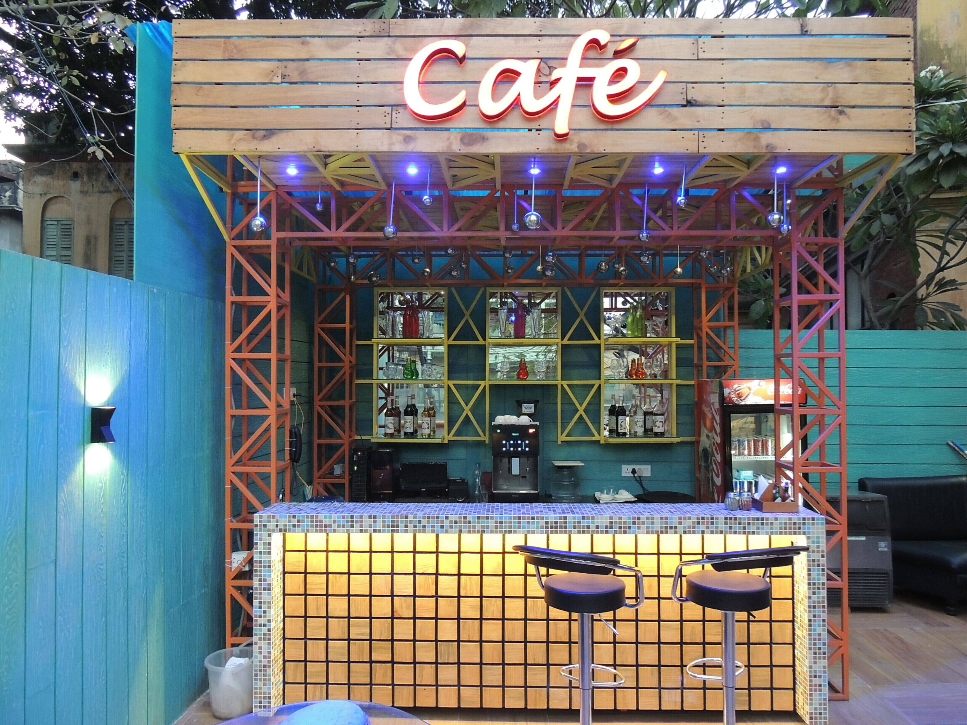 A café with a wooden sign, a tiled counter, and two bar stools.