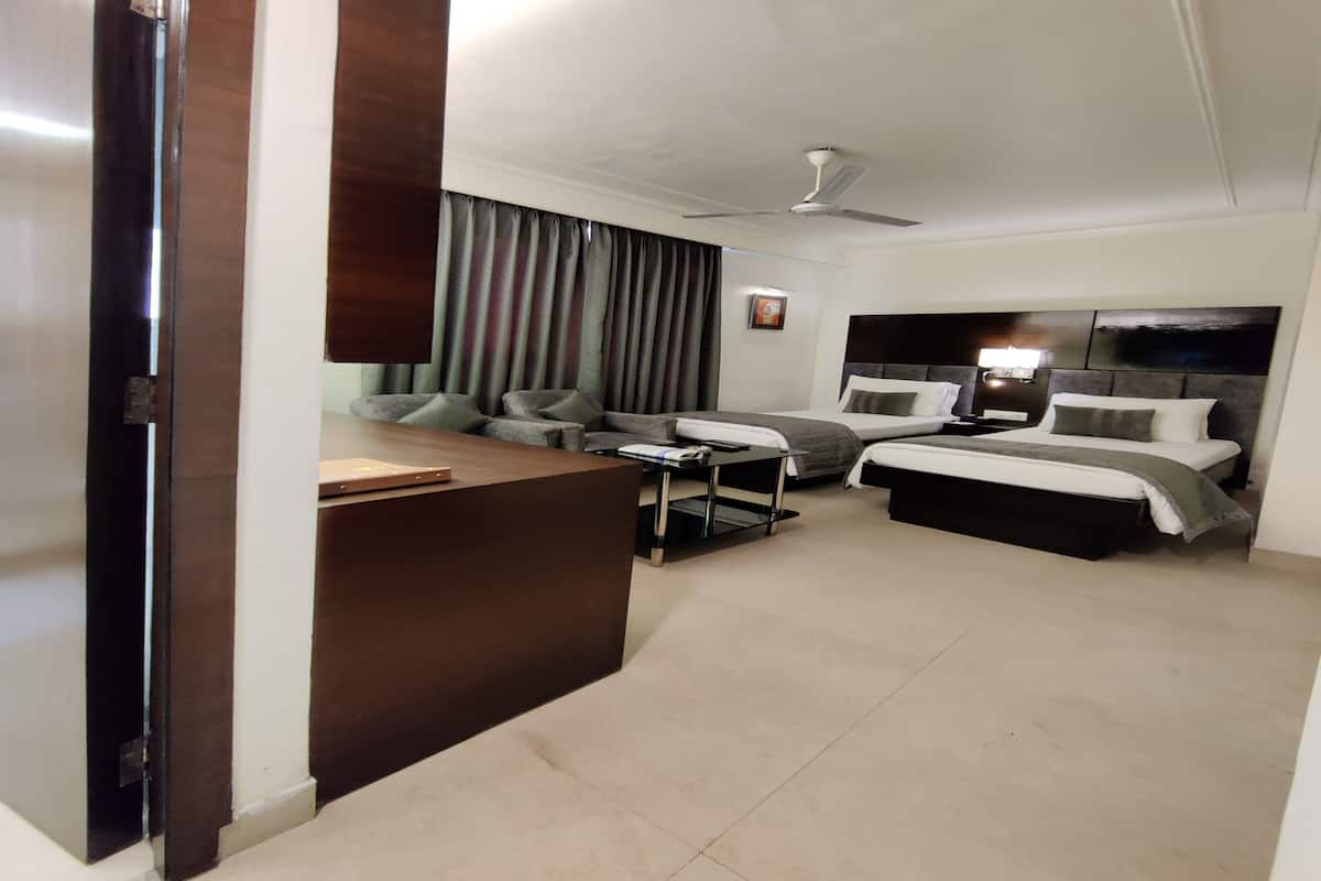 A hotel room with a bed, a desk, a chair, a sofa, and a ceiling fan.