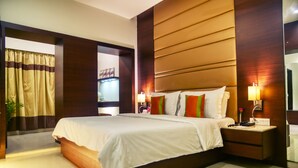 Een moderne hotelkamer met een groot bed, bedlampjes, een nachtkastje en een spiegel.