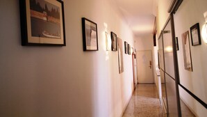 A hallway with framed pictures on the walls, a door at the end, and a refrigerator on the right. - Venezianamente - Casa Cavaletti (Venice)