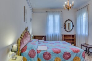 A bedroom with a bed, a nightstand, a dresser, a mirror, and a chandelier. - Venezianamente - Dimora Furlani Canal view (Venice)
