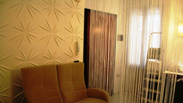A room with a sofa, a curtain, and a wall with a geometric pattern. - Venezianamente-Casa della Crea Canal (Venice)