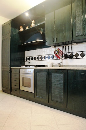 A kitchen with dark wooden cabinets, a stove, and a tiled backsplash.