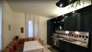 A compact kitchen with a dining area, featuring a microwave, oven, and black cabinets. - Venezianamente-Casa della Crea Canal (Venice)