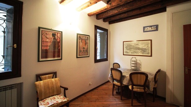 A dining area with wooden beams, a table with chairs, and framed pictures on the walls. - Venezianamente - Residenza Formosa (Venice)