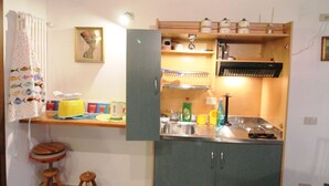 Eine kompakte Küche mit einem eingebauten Kühlschrank, Holzstühlen und Fliesenboden.