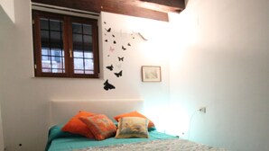 Ein Schlafzimmer mit Bett, Kissen, einem Fenster und Wanddekorationen.