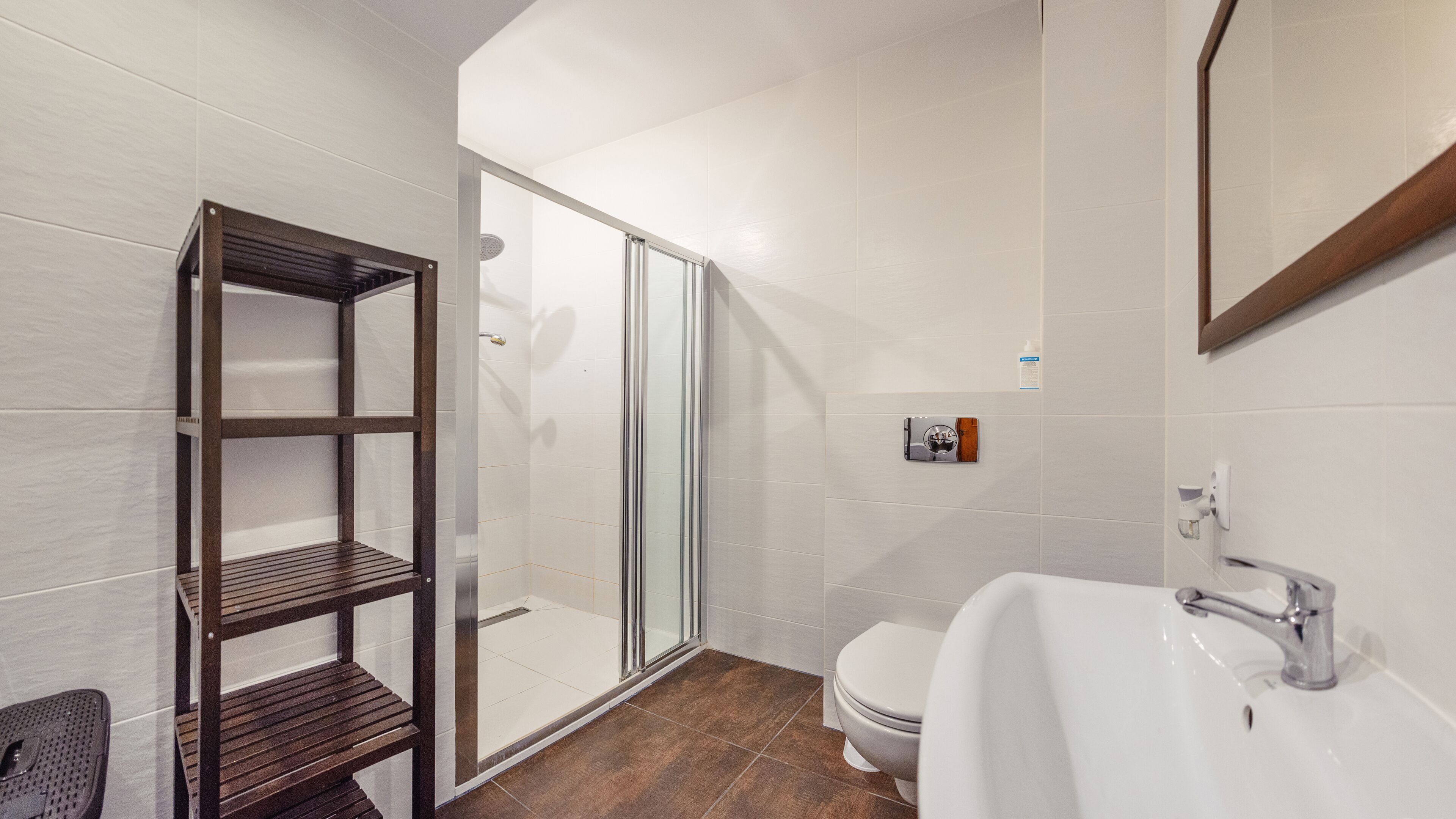 A modern bathroom with a glass shower enclosure, a white toilet, and a white sink with a chrome faucet.