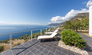 Una terraza en la azotea con dos tumbonas, vistas al mar y un paisaje montañoso.