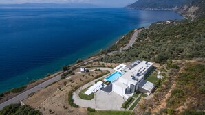 An aerial view of a modern building with a swimming pool, surrounded by a hilly landscape and a coastline. - 600m² homm Luxury Villa Sea Side Evia 16ppl (Istiaia-Aidipsos)
