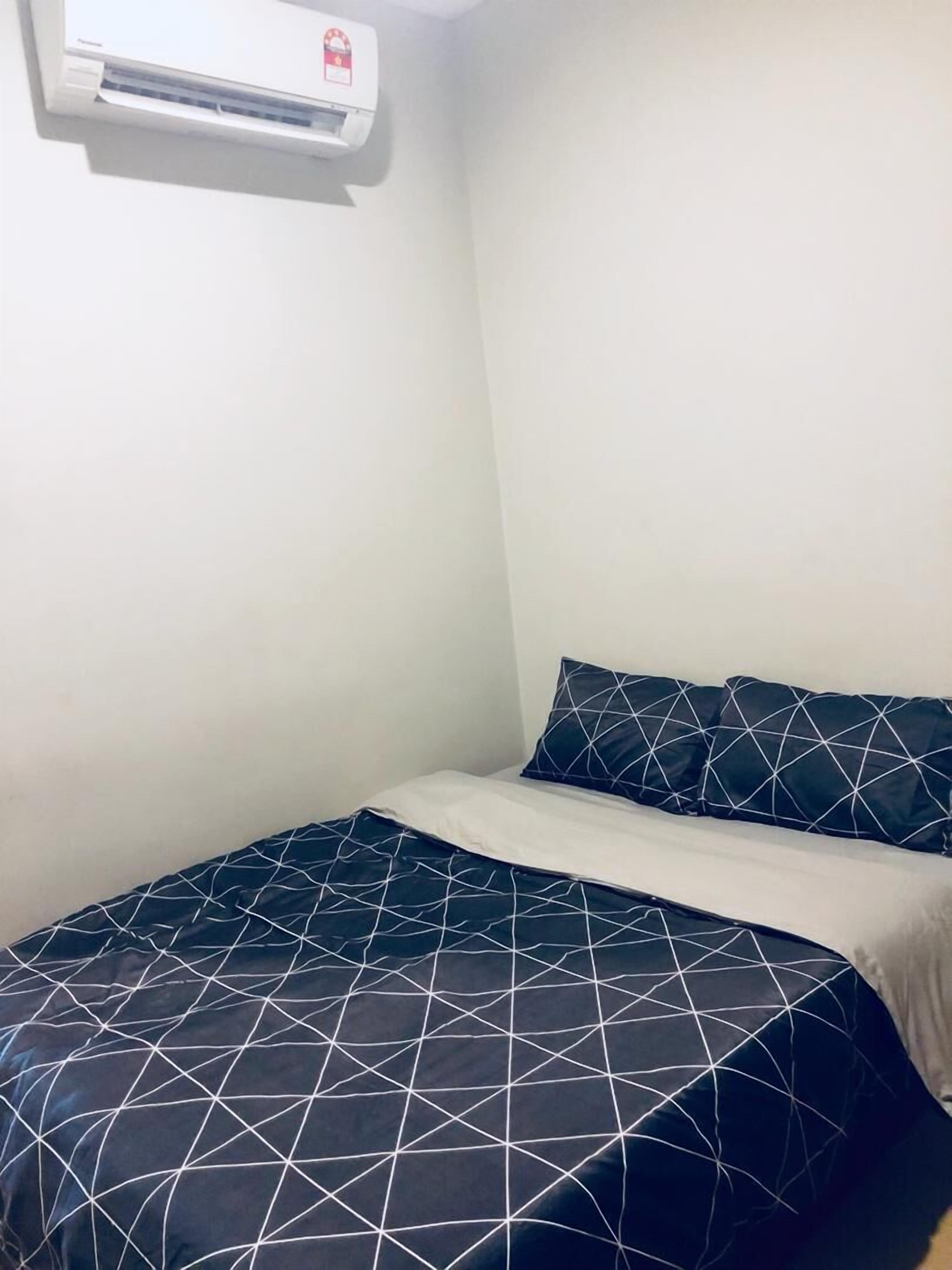A small, simple room with a bed, a pillow, and a wall-mounted air conditioner.