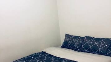 A small, simple room with a bed, a pillow, and a wall-mounted air conditioner.