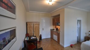 Un espace de vie compact comprenant un coin repas, une kitchenette et une porte donnant sur une autre pièce.